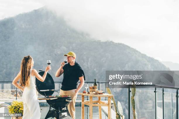 couple having a barbecue outdoors. - couple grilling stock pictures, royalty-free photos & images