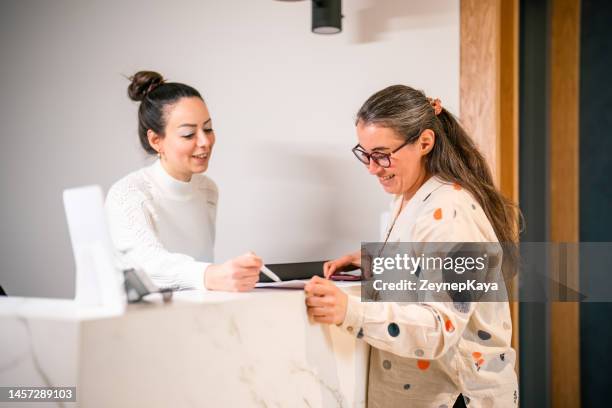 paziente femminile alla reception, compilazione di moduli - accettazione foto e immagini stock