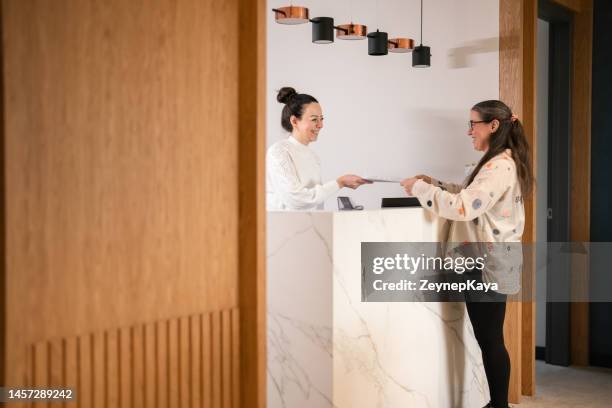 female patient at the front desk, filling forms - receptionist stock pictures, royalty-free photos & images
