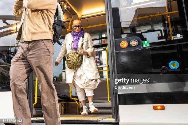 mujer mediana adulta caucásica saliendo del autobús urbano, plano amplio - man riding bus fotografías e imágenes de stock