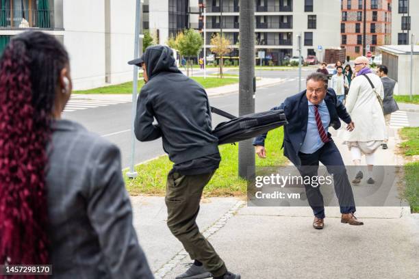 ladro in felpa con cappuccio che ruba la borsa dell'uomo medio adulto sulla strada - pickpocket foto e immagini stock