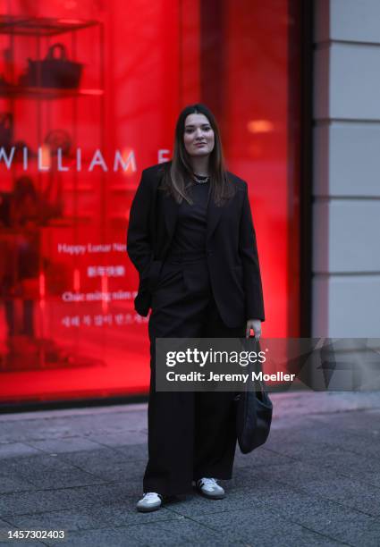 Annika Rogge seen wearing before the William Fan show Adidas samba sneaker, black blazer, black shirt, wide black trousers and a black big bag during...