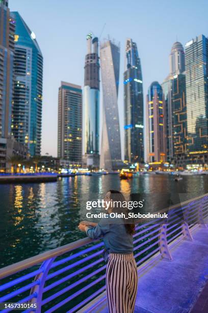 woman walking in dubai marina at sunset - dubai fountain stock pictures, royalty-free photos & images