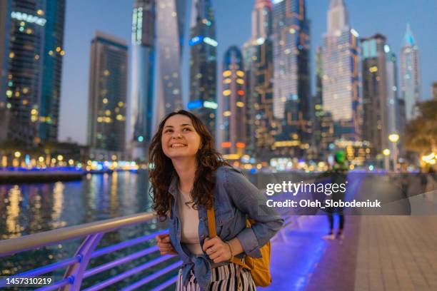 woman walking in dubai marina at sunset - dubai stock pictures, royalty-free photos & images