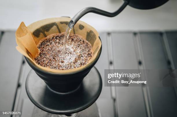 close up of barista pouring hot water on ground coffee with paper filter to making a drip coffee. - ground coffee stock pictures, royalty-free photos & images