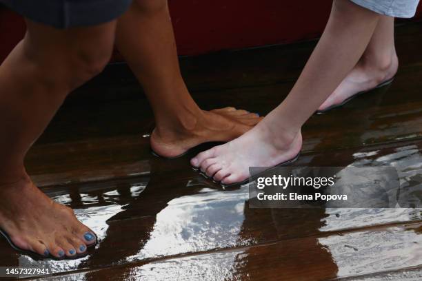 barefoot woman with bunions standing on wet hardwood floor and playing with her son - hallux valgus foto e immagini stock