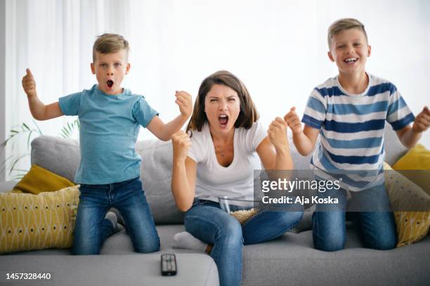 family cheering while watching football on tv. - mom cheering stock pictures, royalty-free photos & images