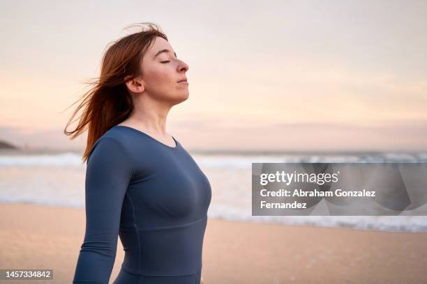 woman breathing with eyes closed on the beach - souffle photos et images de collection
