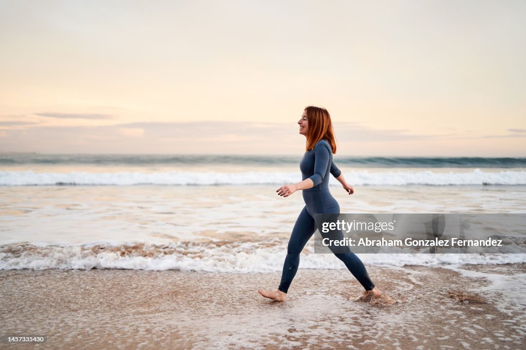 Slim bare foot woman walking along the beach