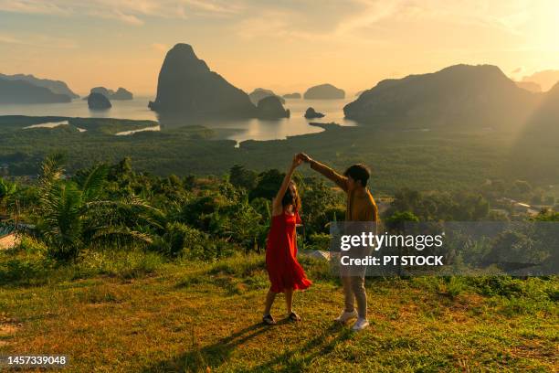 man and woman in red dress holding hands like dancing in view of ao samet nang chee phang nga with sea and mountains in phang nga province, thailand - red sea rain stock pictures, royalty-free photos & images