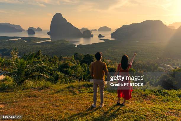 man and woman in red dress holding hands like dancing in view of ao samet nang chee phang nga with sea and mountains in phang nga province, thailand - red sea rain stock pictures, royalty-free photos & images