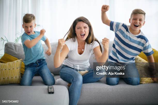 family cheering while watching football on tv. - family watching television stock pictures, royalty-free photos & images