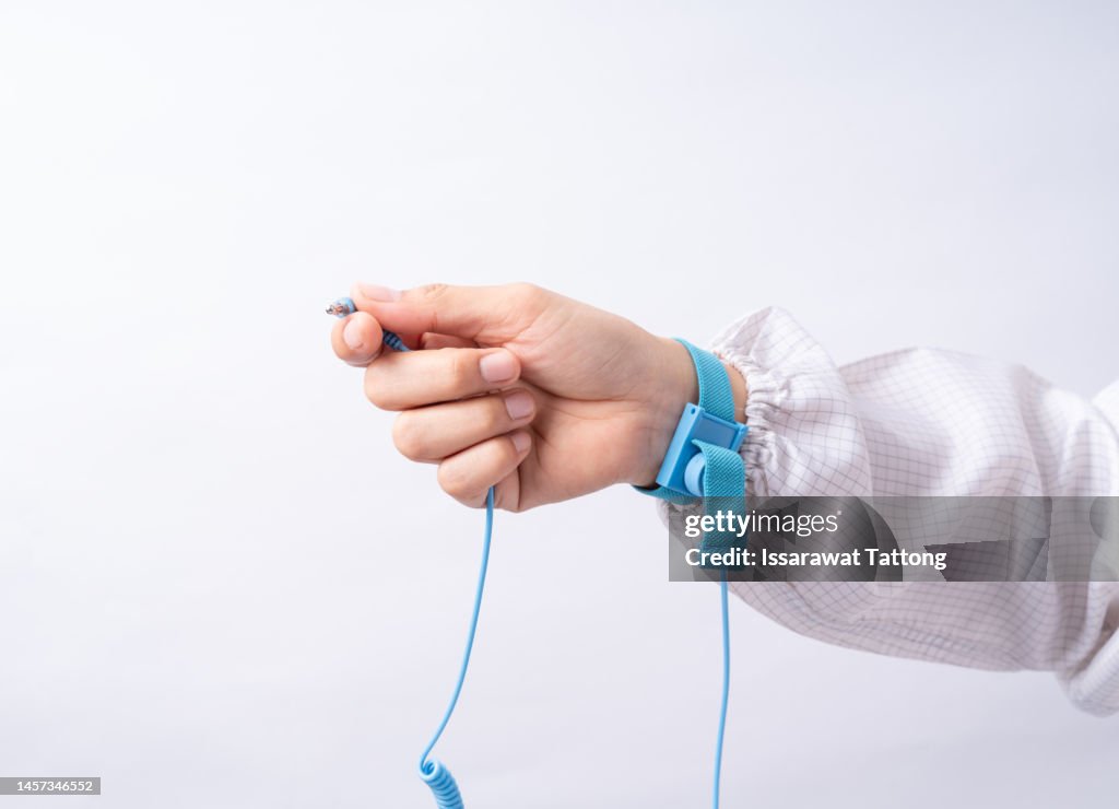 Ground bracelet on man hand wearing ESD cloth white background. Antistatic (ESD) wrist strap or ground bracelet is an antistatic device used to safely ground a person working on electronic equipment.