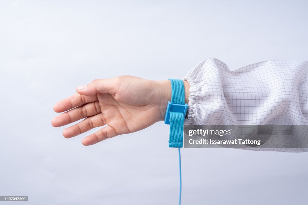 Ground bracelet on man hand wearing ESD cloth white background. Antistatic (ESD) wrist strap or ground bracelet is an antistatic device used to safely ground a person working on electronic equipment.