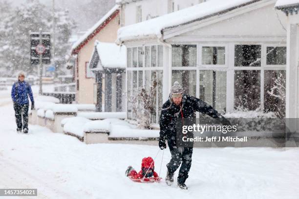 Members of the public make their way through the snow on January 18, 2023 in Carrbridge, United Kingdom. There are five yellow warnings for snow and...