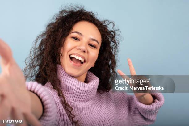selfie of a young black woman on a blue background. portrait of a girl. - one finger selfie stock-fotos und bilder
