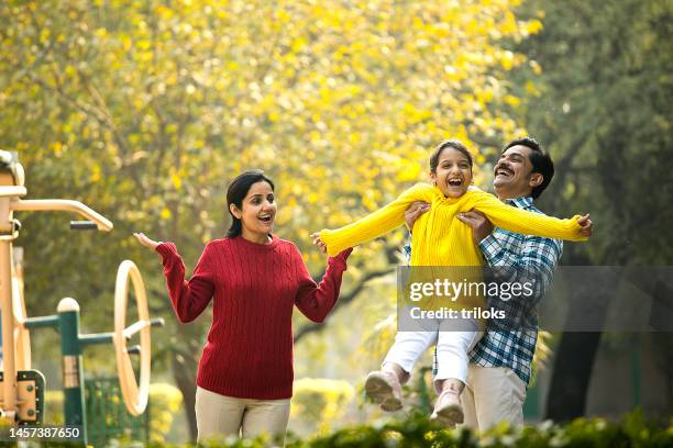 cheerful parents playing with daughter at park - india couple lift stock pictures, royalty-free photos & images