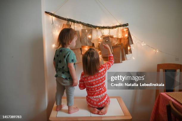 happy children siblings with christmas calendar with gifts. eco-friendly advent calendar. christmas waiting calendar for children from paper bags and tree branches. - advent stock-fotos und bilder