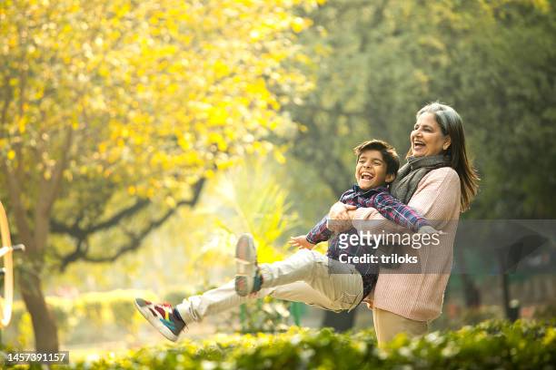 fröhliche großmutter spielt mit enkel im park - asian granny pics stock-fotos und bilder