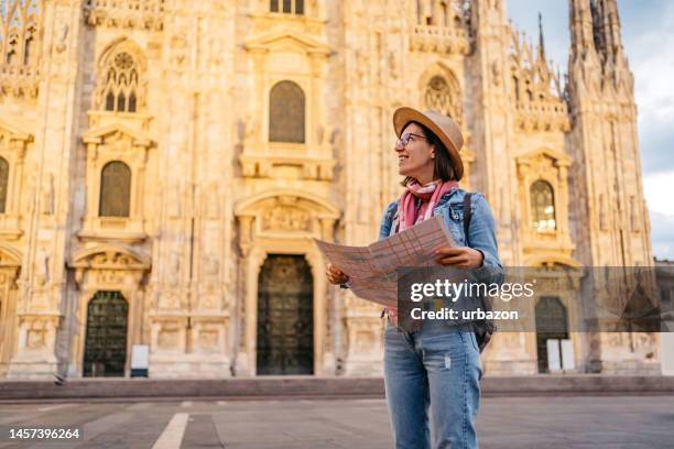 young female tourist using a map in front of cathedral in milan - milan map stock pictures, royalty-free photos & images