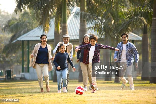 mehrgenerationenfamilie spielt fußball im park - indian family stock-fotos und bilder