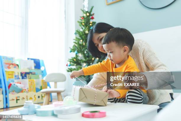 asian mother and her little son wrapping christmas presents - birthday present stock pictures, royalty-free photos & images