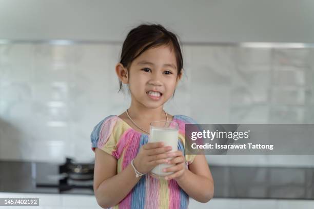 adorable baby girl dringking milk with the glass - asian child with new glasses stockfoto's en -beelden