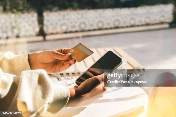 woman using a credit card to pay online bills using mobile application - tarjeta de lealtad fotografías e imágenes de stock