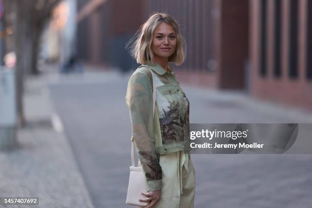 Olga Löffler seen wearing a total Marc Cain look with a green printed blouse and matching pants, a pink long coat, heels and a leather bag during the...