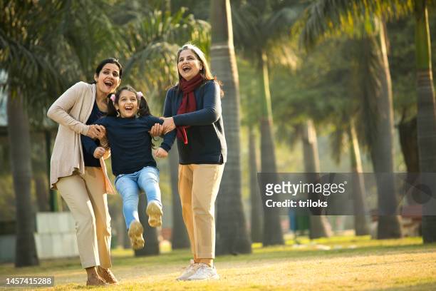 three generations of cheerful females having fun at park - indian mother daughter stock pictures, royalty-free photos & images