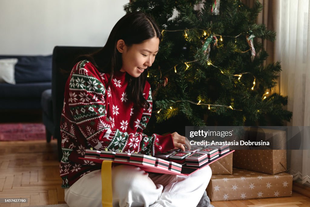 Young adult asian woman opening gift boxes of Christmas advent calendar