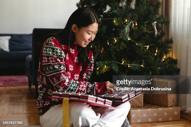 young adult asian woman opening gift boxes of christmas advent calendar - advent calendar stock pictures, royalty-free photos & images