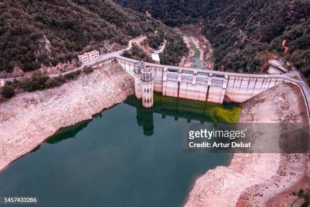 aerial view of the reservoir dam with the lowest water level due the critical drought in spain. - low concept stock-fotos und bilder