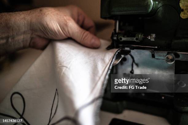 close-up of a senior man using a sewing machine at home - restauratiestijl stockfoto's en -beelden