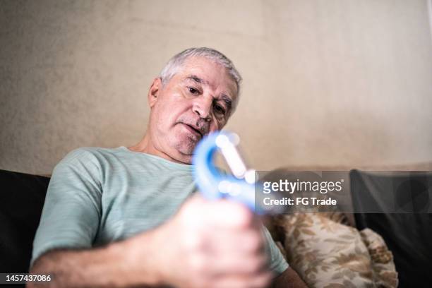 älterer mann mit handgriff zu hause - sehnenscheidenentzündung stock-fotos und bilder