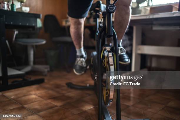 low section of a man exercising on exercise bike at home - exercise bike stock pictures, royalty-free photos & images