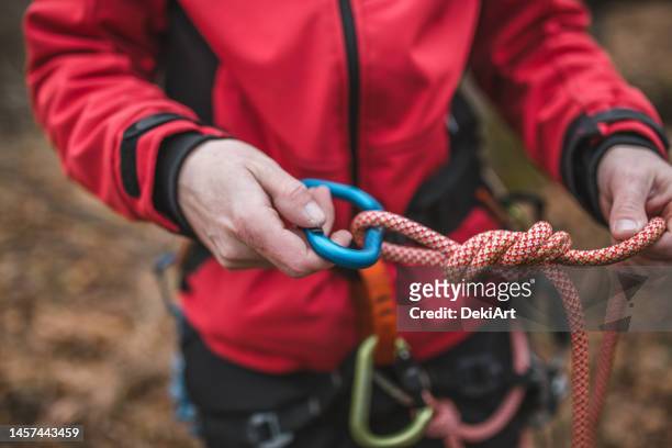 close-up of the hands of a mountain service rescuer tying a knot on a rope, ready to go on a rescue mission - mountain climbing equipment stock pictures, royalty-free photos & images