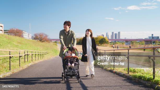 family enjoying warm weather and taking a walk together - baby pram in the park stock pictures, royalty-free photos & images