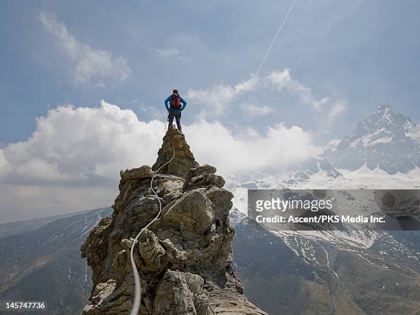 climber stands on top of pinnacle, rope connects - pinnacle stockfoto's en -beelden