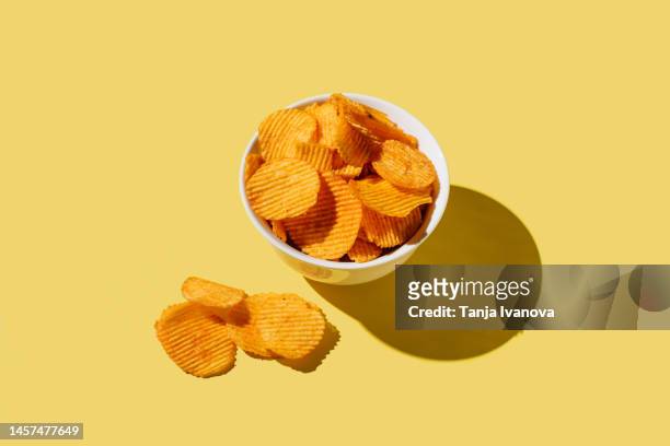 plate of potato chips on yellow background. flat lay, top view, copy space - crisps foto e immagini stock