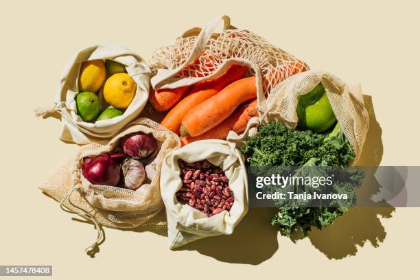 variety fresh of organic fruits and vegetables and healthy vegan meal ingredients in reusable eco cotton bags on beige background . zero waste shopping concept. healthy food, clean eating, eco friendly, no plastic. flat lay, top view - supermarket foto e immagini stock