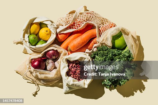 Variety Fresh of organic fruits and vegetables and healthy vegan meal ingredients in reusable eco cotton bags on beige background . Zero waste shopping concept. Healthy food, clean eating, eco friendly, no plastic. Flat lay, top view