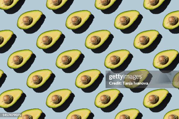 pattern of fresh ripe green avocado fruit halves on blue background. healthy food, diet and detox concept. flat lay, top view - seamless pattern stock pictures, royalty-free photos & images