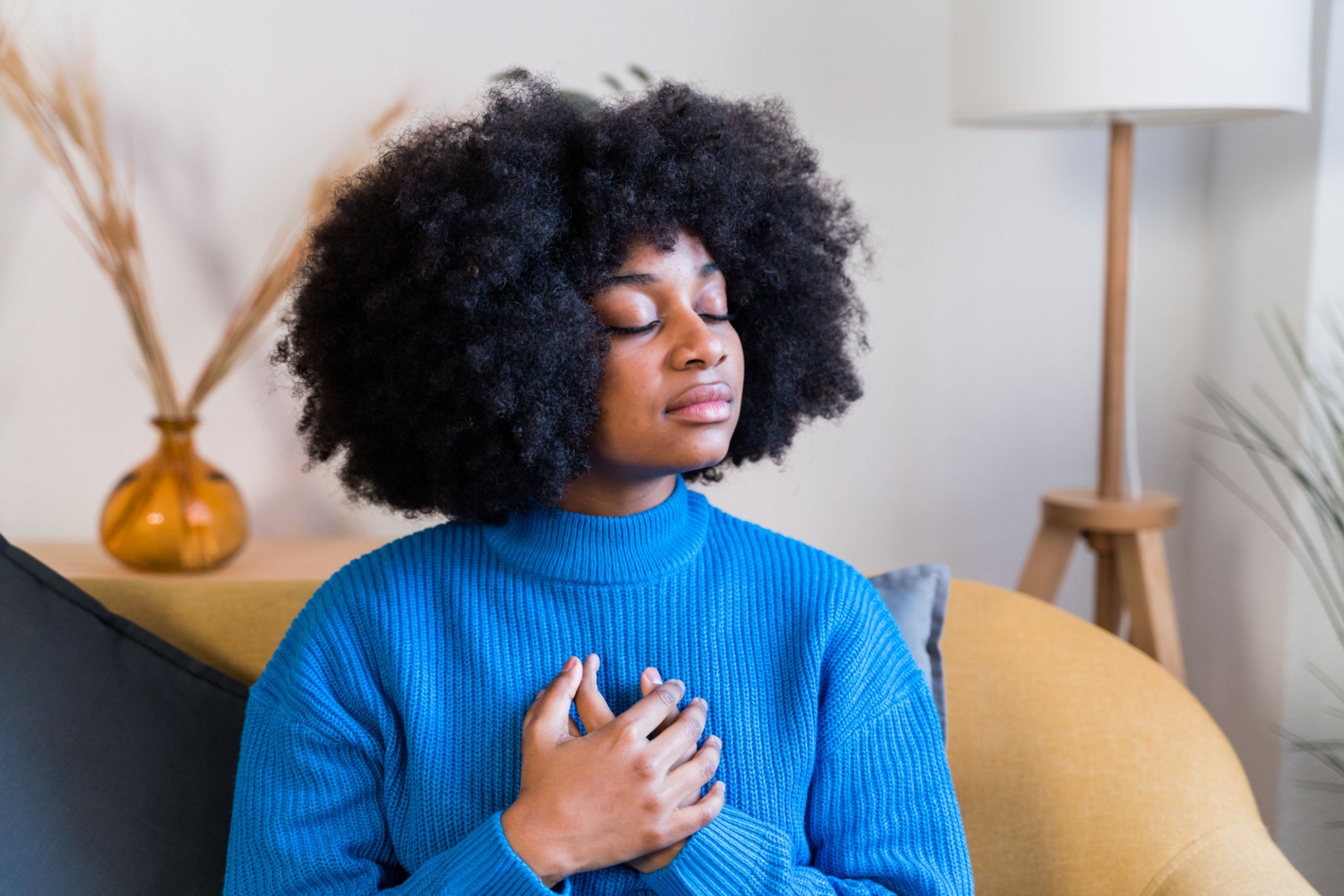 Black woman with curly hair meditating at home Black woman with curly hair meditating at home