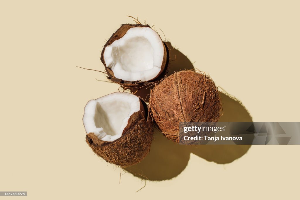 Ripe coconuts on beige background. Creative summer concept. Half of coconut in minimal flat lay style. Top view