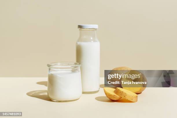 potato milk alternative plant based dairy drink in glass bottle and glass and potato tubers on beige background. healthy vegetarian and vegan drink concept. lactose-free milks in minimal style, copy space. - milk plant stock-fotos und bilder