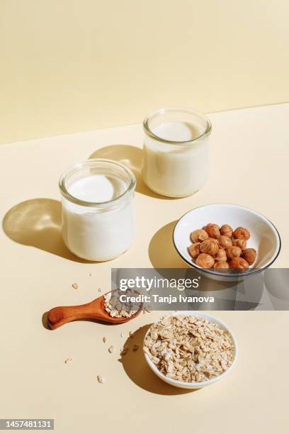 various organic vegan plant based milk in glasses and ingredients (nuts, oatmeal) on beige background. non dairy milk substitute drink, healthy eating. lactose-free milk in minimal flat lay style. top view - dairy product stock-fotos und bilder