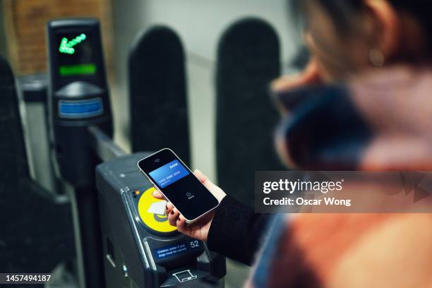 young woman making contactless payment with smartphone at train station - london underground train stockfoto's en -beelden