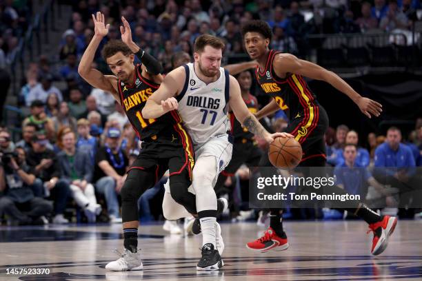 Luka Doncic of the Dallas Mavericks dribbles the ball against Trae Young of the Atlanta Hawks and De'Andre Hunter of the Atlanta Hawks in the first...