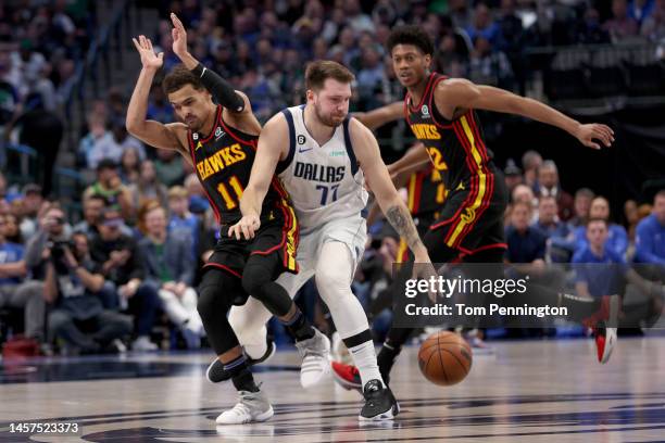 Luka Doncic of the Dallas Mavericks dribbles the ball against Trae Young of the Atlanta Hawks and De'Andre Hunter of the Atlanta Hawks in the first...